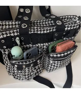 Detail view of houndstooth tote bag featuring functional zippered pockets and metal grommets