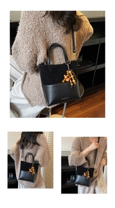 Detail of black suede and smooth leather bucket bag with wooden tassel and brand logo