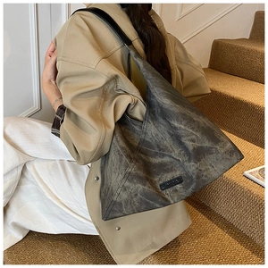 Detailed macro view of gray marbled suede texture and logo patch on tote bag