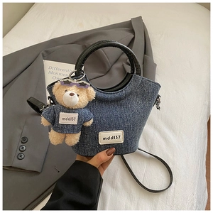 Détail du sac en jean bleu avec poignées en cuir et pendentif ours mignon