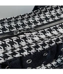 Close-up of houndstooth fabric bag featuring a metal zipper pull and silver eyelet details