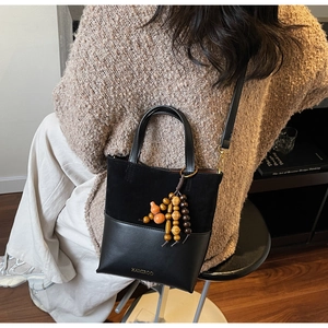 Detail of suede contrast bucket bag with vintage wooden gourd pendant and gold logo