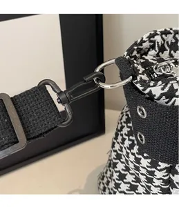 Detail of detachable black metal hook and adjustable strap on houndstooth crossbody bag