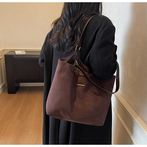 Détail d'un sac cabas marron vintage en suède avec barre métallique et bandoulière