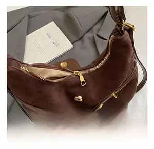 Detail showing high-quality gold hardware zipper and buckle on brown suede bag