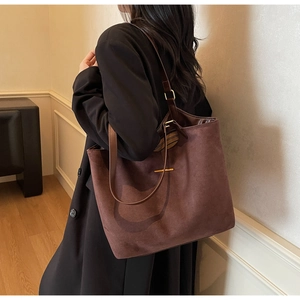 Détail du grand sac cabas en daim marron foncé avec boucle dorée élégante et texture douce