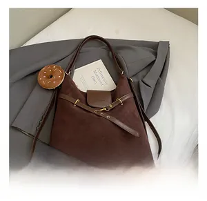 Detailed shot of dark brown suede tote bag with metal buckle and donut charm