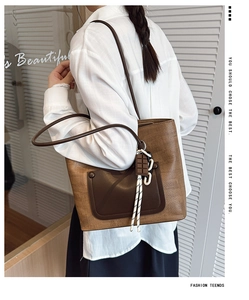 Detail of a brown textured faux leather tote bag with unique chocolate charm and woven rope