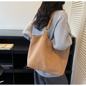 Grand sac cabas en daim marron porté par un mannequin, montrant sa capacité spacieuse