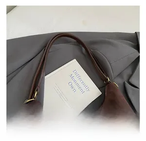 Detail of dark brown suede shoulder bag featuring a plush star charm and logo embossing