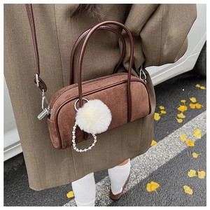 Close-up of brown suede mini bowling bag with white fur ball and pearl chain details