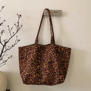 Close-up of leopard print suede tote bag with durable shoulder straps on a wall hook