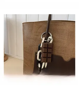 Close-up of woven tote bag featuring a leather pocket and chocolate shape charm detail
