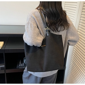 Détail d'un grand sac cabas noir en daim montrant la texture et les anses en cuir