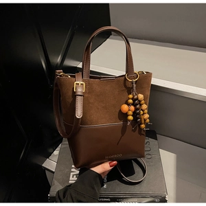 Detail of brown leather and suede bucket bag featuring ethnic style wooden bead charm