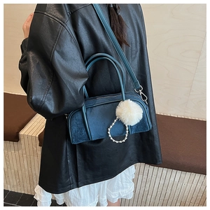 Detail of blue suede bowling bag with fluffy white pompom and pearl chain accessory