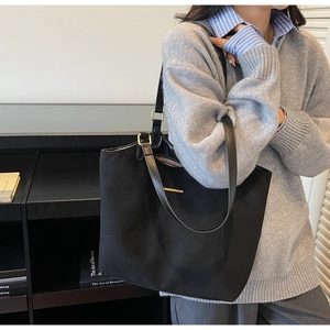 Vue détaillée d'un sac cabas noir avec garniture dorée porté par un mannequin