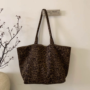 Detail of leopard print suede tote bag hanging on a white wall with minimalist decor