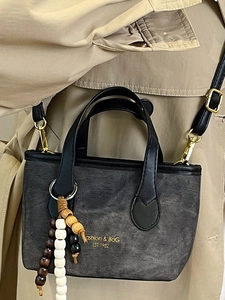 Minimalist black textured tote bag with beaded pendant and gold Fashion & Bag lettering