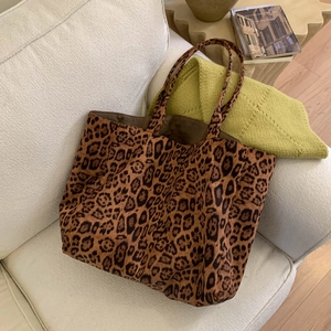 Detailed view of leopard print suede tote bag on a white sofa with cozy French vibes