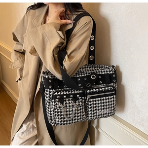 Detail of plaid tote bag with silver metal rivets and chain on model in trench coat