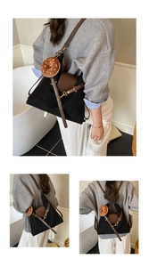 Close-up of black canvas backpack with brown leather flap and donut charm detail