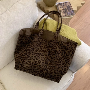Macro shot of durable leopard print fabric texture and sturdy tote bag handles on a sofa