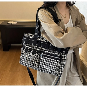 Close-up of houndstooth tote bag detail with metal rivets and chains on functional pockets