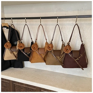 Detail view of suede tote bags in five colors with plush donut charms on a display rack