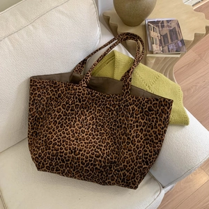 Detailed macro view of large leopard print tote bag placed on a cozy white sofa