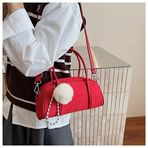 Detail of red faux suede bowling bag with white pompom and pearl chain on a model