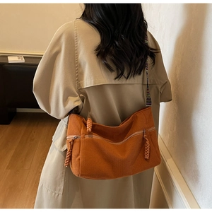 Detail of caramel corduroy tote with colorful ethnic woven shoulder strap shown on model