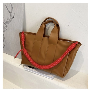 Close-up of brown PU leather tote bag with a striking red woven rope shoulder strap