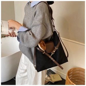 Detail of black canvas tote bag with brown leather V-strap and donut plush charm