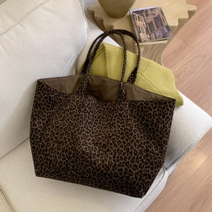 Top view of high capacity leopard print suede tote bag on a cozy white fabric sofa