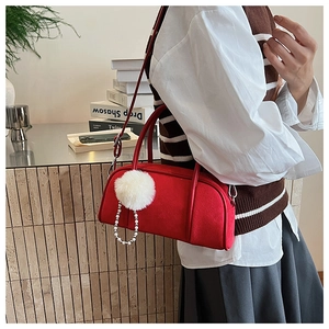Detailed side view of a red suede bowling bag with white faux fur pom and pearl chain