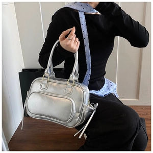 Detail of silver metallic Boston bag held by model showing texture and zipper details