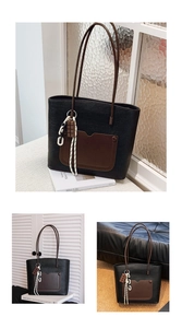 Detail of a large textured black tote bag with brown pocket and stylish charms