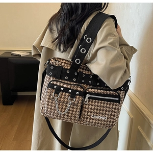Detail view of houndstooth tote bag with metal chain accents and wide webbing strap