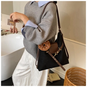 Detail of suede backpack with brown leather strap and donut plush charm accessory