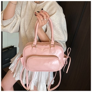 Detailed view of a pink Boston bag featuring a stylish bow drawstring and glossy PU leather
