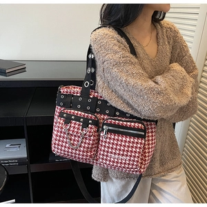 Detail of red houndstooth tote bag featuring metallic grommets and silver chain accents