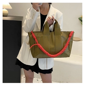 Close-up of olive green tote bag featuring a vibrant red braided rope handle detail