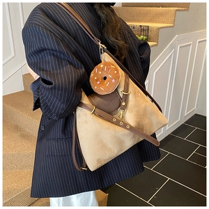 Close-up of suede tote bag with leather straps and a decorative donut plush charm