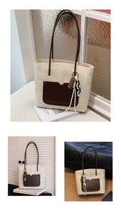 Detail of a large woven tote bag with brown leather handles and a chocolate charm