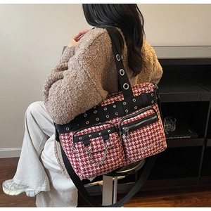 Detail of red and white houndstooth tote bag featuring metal eyelets and chain accents