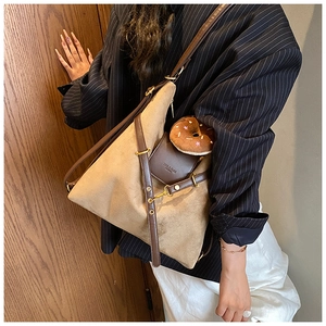 Detail of khaki suede tote bag with brown leather straps and gold metal hardware