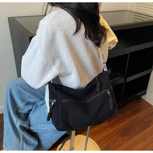 Detail of black corduroy tote bag with colorful woven strap on a female model