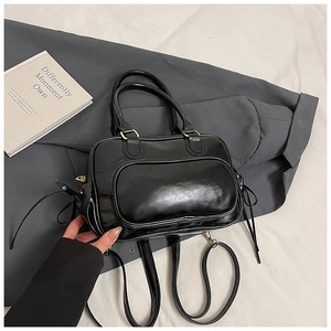 Detail of black glossy leather Boston bag showing smooth texture and multifunctional straps