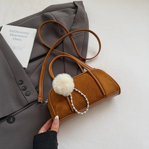 Detail view of brown suede bowling bag with white fur pompom and pearl chain accents
